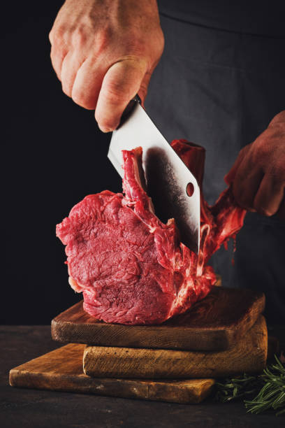 istock Male butcher cuts raw beef meat. 1199735609