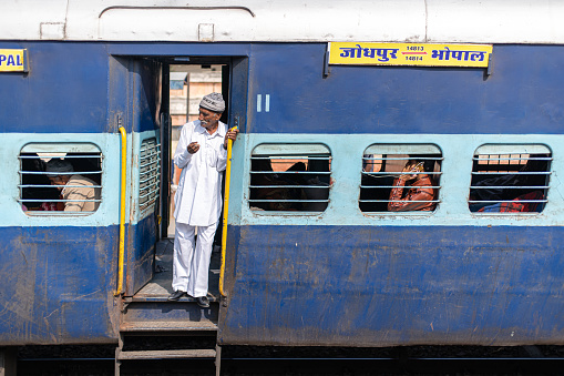 Jodhpur, India - December 10, 2019: A man standing in the door of an Indian train.
