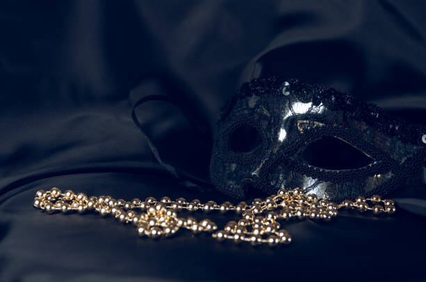 istock Carnival accessory on a fabric background. Black mask and beads 1199740681