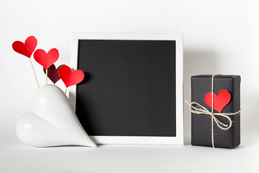 Black red white color palette mockup composition with black blank frame, heart, wrapped present for Mothers, Fathers, Valentine's day.