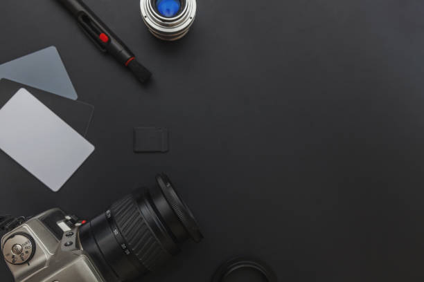 istock Photographer workplace with dslr camera system, camera cleaning kit, lens and camera accessory on dark black table background. Hobby travel photography concept. Flat lay top view copy space 1199740907