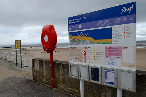 Rhyl, UK: Jan 7, 2020: A lifebouy holder and beach information sign on the promenade.