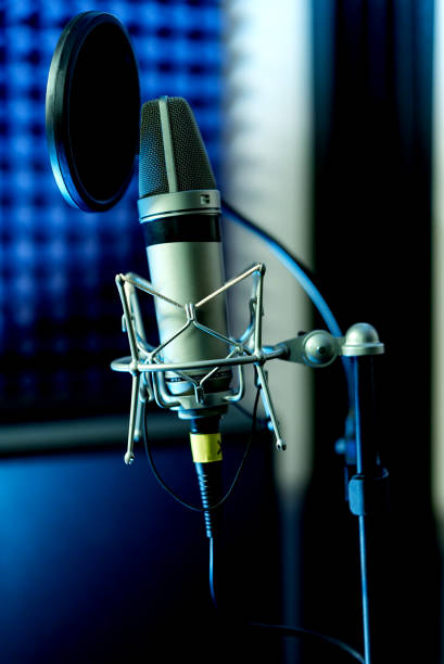 istock Close up studio condenser microphone with pop filter and anti-vibration mount live recording with color lights background. Side view 1199742683