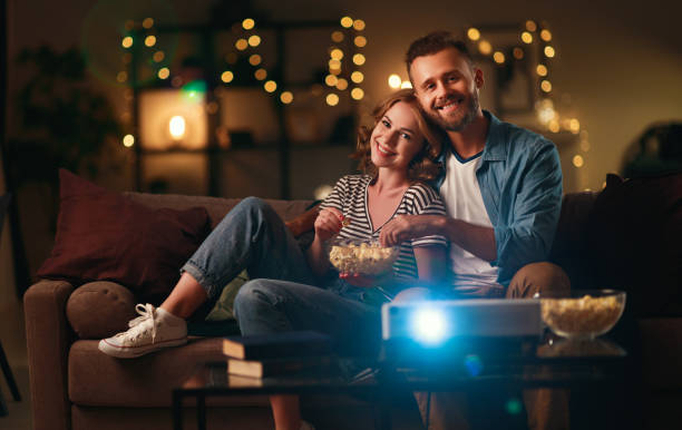 istock Family couple watching television projector at home on sofa 1199745156