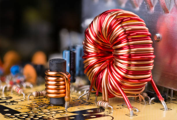 inductor copper wire winding. toroidal and cylindrical ferromagnetic induction coils. electrotechnics, electrotechnology - service electronics industry circuit board capacitor imagens e fotografias de stock