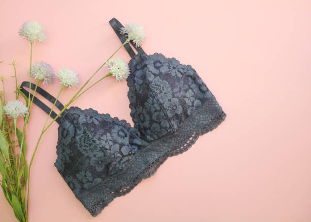 Koronkowy czarny biustonosz na różowym tle w delikatne białe kwiaty, symbolizujący zmysłowość i elegancję.