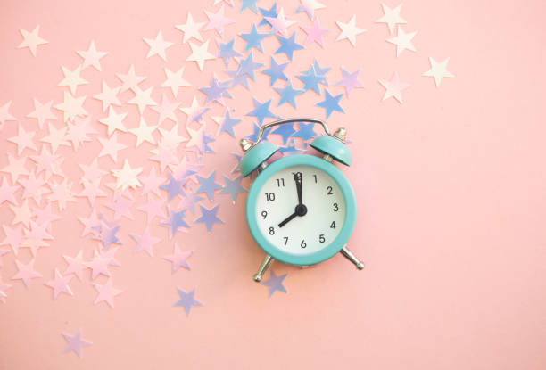 istock Vintage alarm clock on pink background with star shiny confetti 1199745862