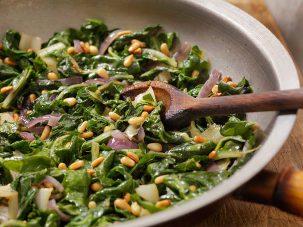 garlic and butter sautéed swiss chard with toasted pine nuts - acelgas imagens e fotografias de stock