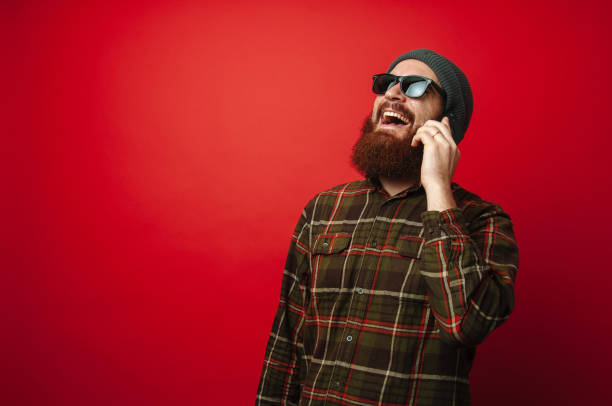 istock Smiling bearded hipster man talking on smartphone 1199749417