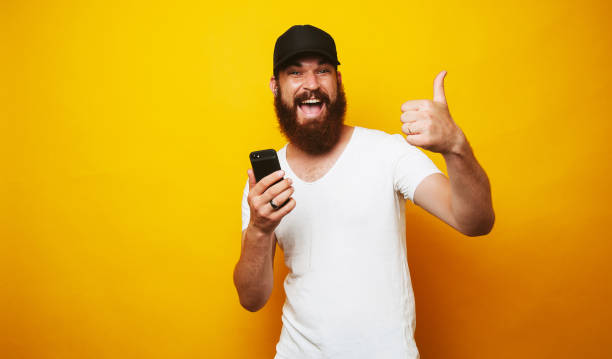 istock Amazed man holding smartphone and showing thumbs up 1199749960