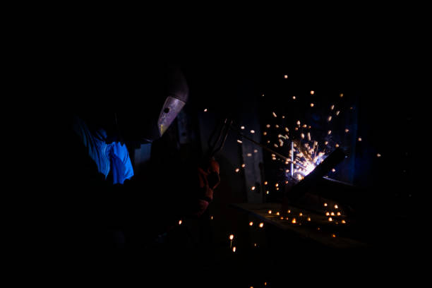 welder doing metal work at night, front and background blurred with bokeh effect welder doing metal work at night, front and background blurred with bokeh effect welder engineering construction bright stock pictures, royalty-free photos & images