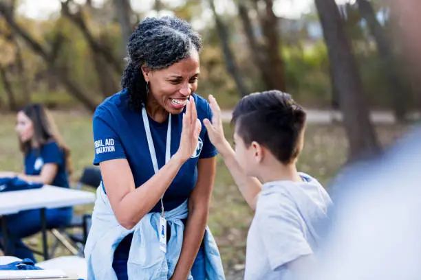 Photo of Mature adult woman gives boy high five for volunteering