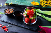 Close up image of a dessert strawberries in a glass, chocolate and crisps in small bowls.