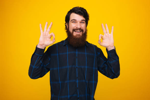 istock Handsome bearded man making ok gesture with both hands on yellow background. 1199758723