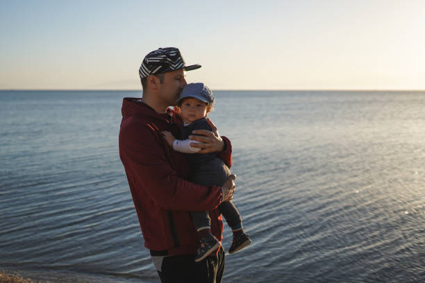 Young father playing with baby girl on beach