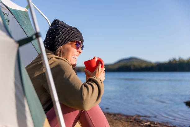 istock Young Women drinking Coffee by the Lake in Camping 1199770362