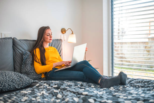 istock Beautiful woman using laptop on bed at home 1199773515