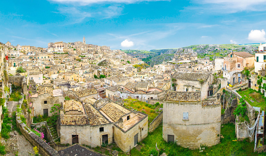 Aerial panoramic view of Matera historical city centre Sasso Caveoso, old ancient town Sassi di Matera with rock cave houses buildings, blue sky background, Basilicata, Southern Italy
