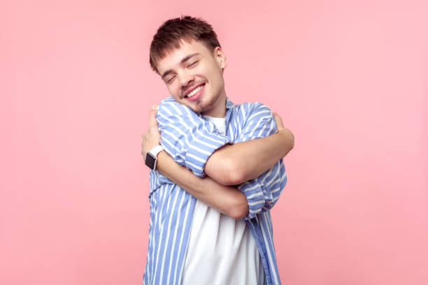 portrait of happy selfish brown-haired man with small beard and mustache embracing himself. isolated on pink background - urgency body care young adult people imagens e fotografias de stock