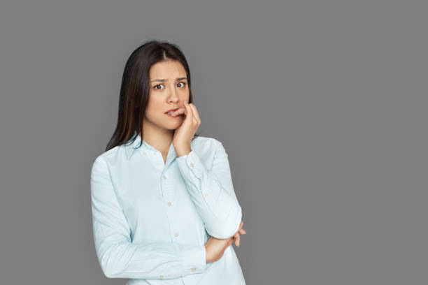 istock Freestyle. Young woman standing isolated on grey biting nails nervous 1199774052