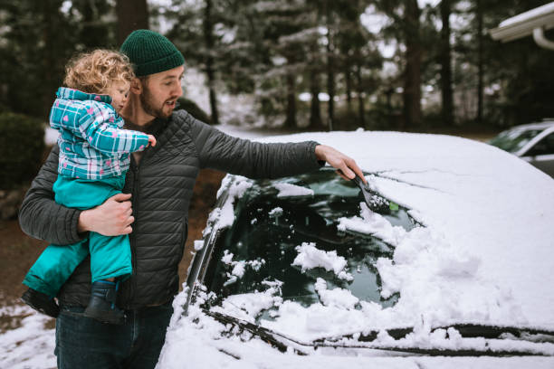 父と幼児の老人少女は車から雪を削る - scraper ストックフォトと画像