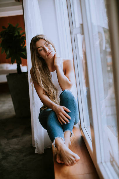 istock Beautiful young woman sitting by the window 1199777549