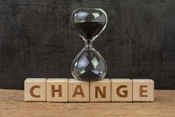 istock Change, transform or evolve to success in disruption world concept, sand glass or hourglass on cube block with alphabet building the word Change on wood table with dark black background 1199779987