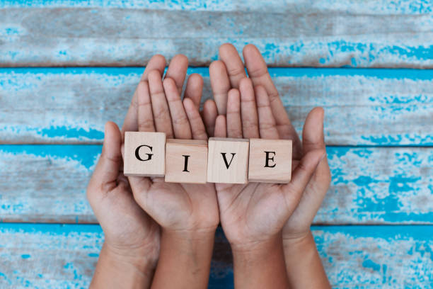 alphabet letter wooden blocks with words give in child and parents hands. family and charity concept - entregando imagens e fotografias de stock