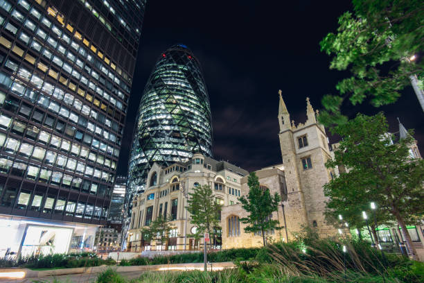 30st Mary Axe Building in London at Night Night View of the Iconic Gherkin Building in the City of London and Historic St. Andrew Undershaft Church. gherkin london night stock pictures, royalty-free photos & images