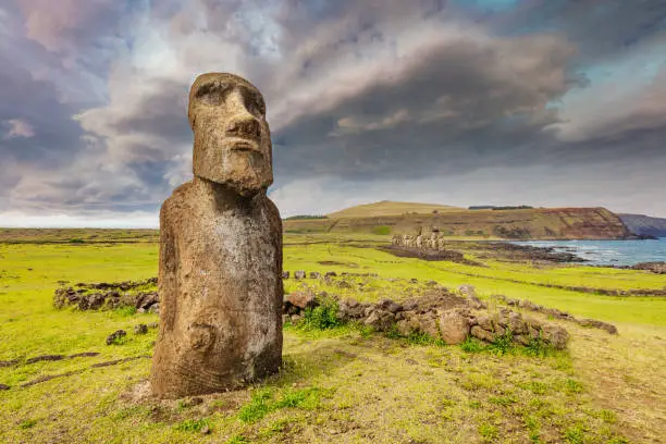 Ahu Tongariki Traveling Moai with Easter Island Tongariki Moai Statues in the background under beautiful skyscape.  The 'Travelling Moai' has wandered the most of any Moai on the island. It has been brought to Japan for  world fair, returned, and has been used in walking-experiments by Thor Heyerdahl to determine how the inhabitants originally moved the Moais. Ahu Tongariki, Rapa Nui National Park, Hanga Roa, Easter Island, Chile.