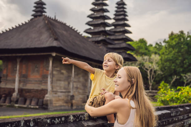 maman et fils touristes dans le temple traditionnel balinais hindou taman ayun à mengwi. bali, indonésie voyager avec des enfants concept - zen like women temple meditating photos et images de collection
