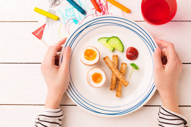 istock Breakfast in child's hands - eggs, toasts and cucumber 1199811871