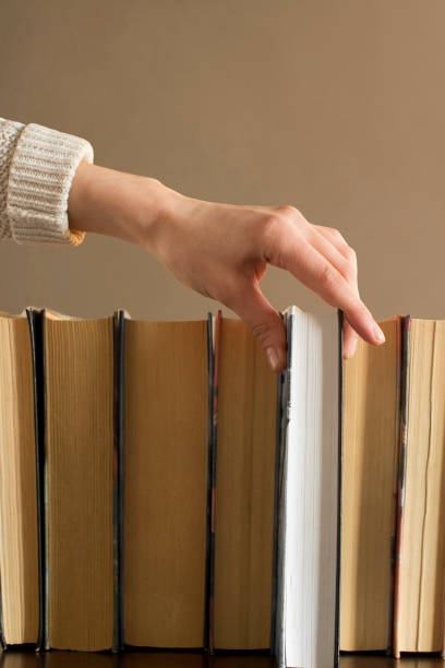 istock young woman choosing a book from a bookshelf 1199813074