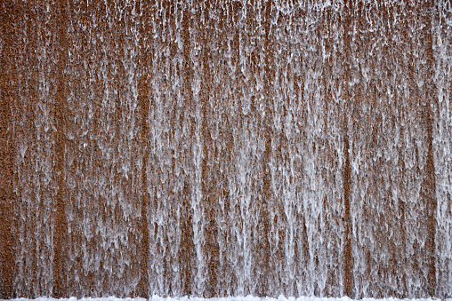 Surface of brown stone with falling water background.