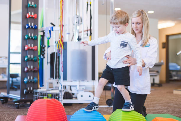 istock Young boy doing a fun exercise with a physical therapist at a clinic 1199815703