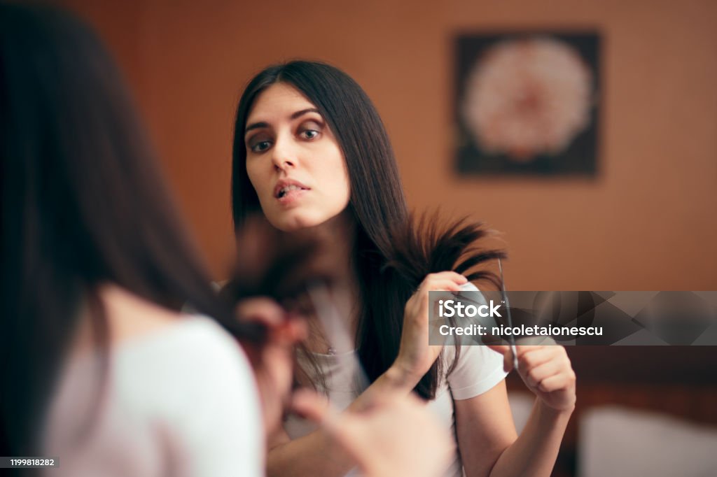 Woman Looking in Mirror Cutting Split Hair Ends Girl changing looks giving herself a with DIY cut Hair Stock Photo