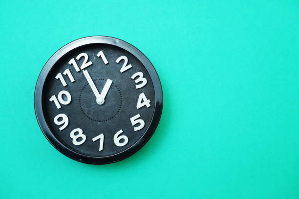 istock Black round clock showing Ten o'clock on green background 1199820392