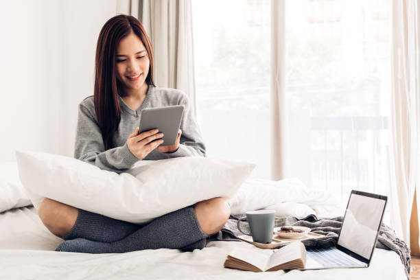 istock Happy woman relaxing using tablet computer on the bed at home.technology and communication concept 1199820623