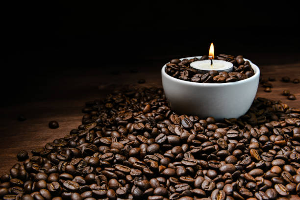 istock White coffee cup full of coffee beans and burning candle on top of coffee bean stack 1199824976