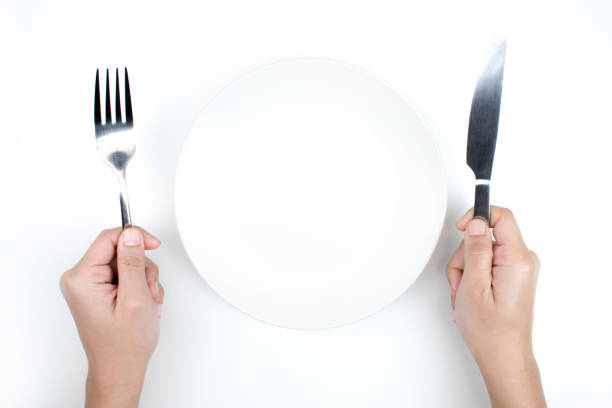 istock Restaurant and Food theme. A hand holding a spoon and an empty plate on a white background. 1199826529
