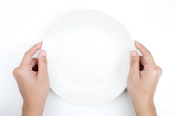 istock The hand is holding an empty plate on the white blackground. 1199826542