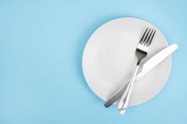 top-ansicht platte mit einem löffel auf dem blauen hintergrund. - plate silverware fork table knife stock-fotos und bilder