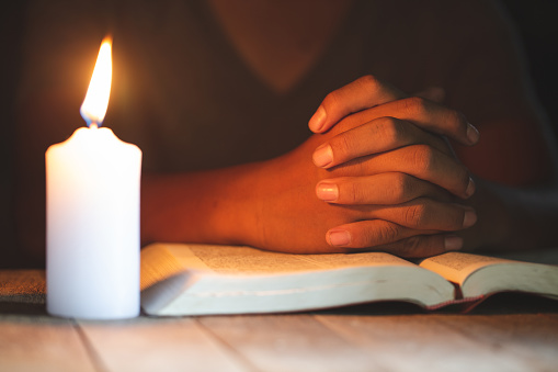 Religious concepts, The young man prayed on the Bible in the room and lit the candles to illuminate.