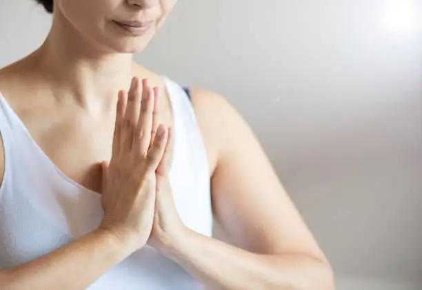 Woman meditating and praying in the small yoga studio.