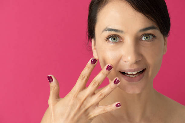 Smiling woman with pink polish on the pink background.