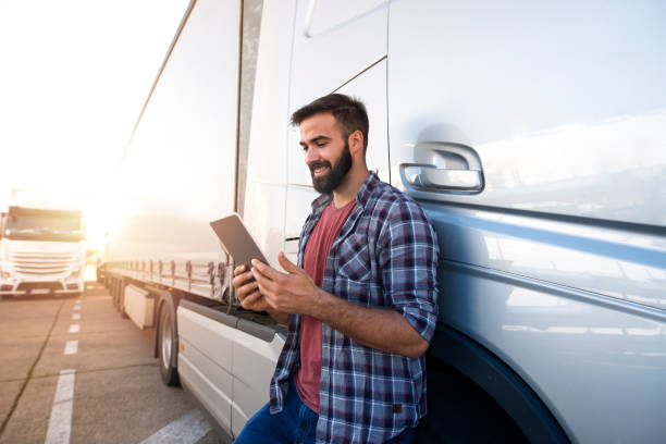 Truck driver and transportation service. Professional truck driver checking his route on tablet computer and standing by long vehicle. Transportation service. truck driver stock pictures, royalty-free photos & images