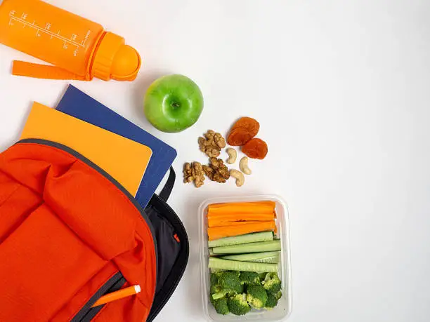 Photo of School lunch box with vegetables on a white background, top view.