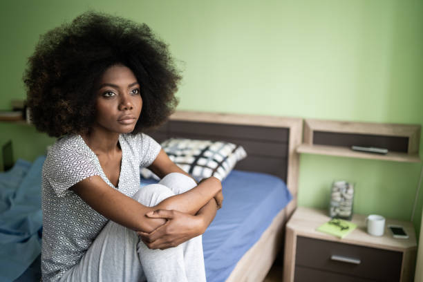 istock Sad afro woman sitting on a bed 1199830979