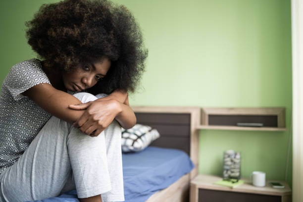 istock Sad afro woman sitting on a bed 1199830980