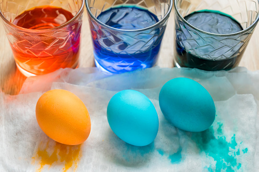 Easter Egg Dying Process. Transparent glass cups with colored water and Colored eggs , top view